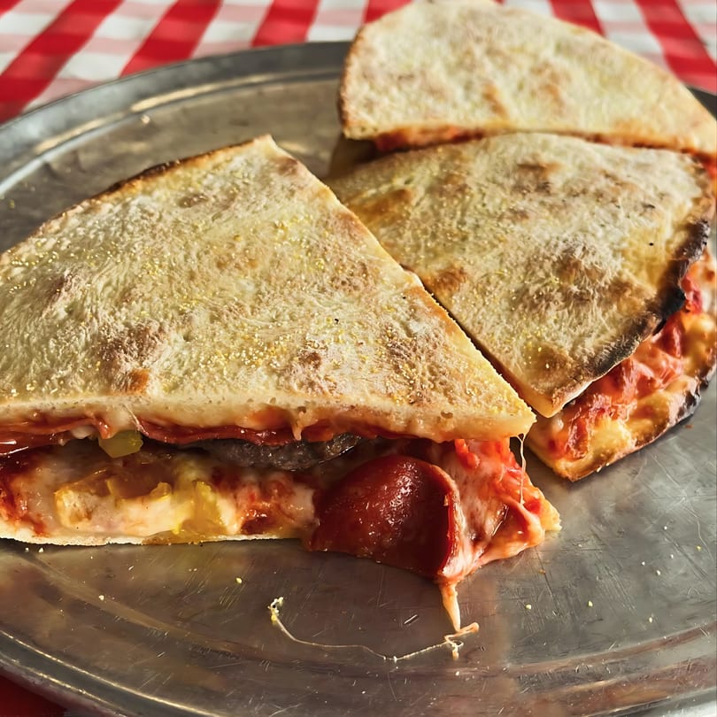 Three slices of Jake's Pizza Rostraver's pepperoni and cheese stuffed pizza on a metal tray.