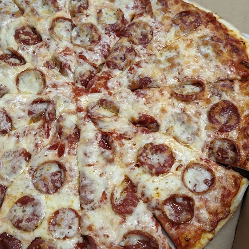 Close-up of a freshly baked Jake's Pizza Rostraver pepperoni pizza, cut into slices.